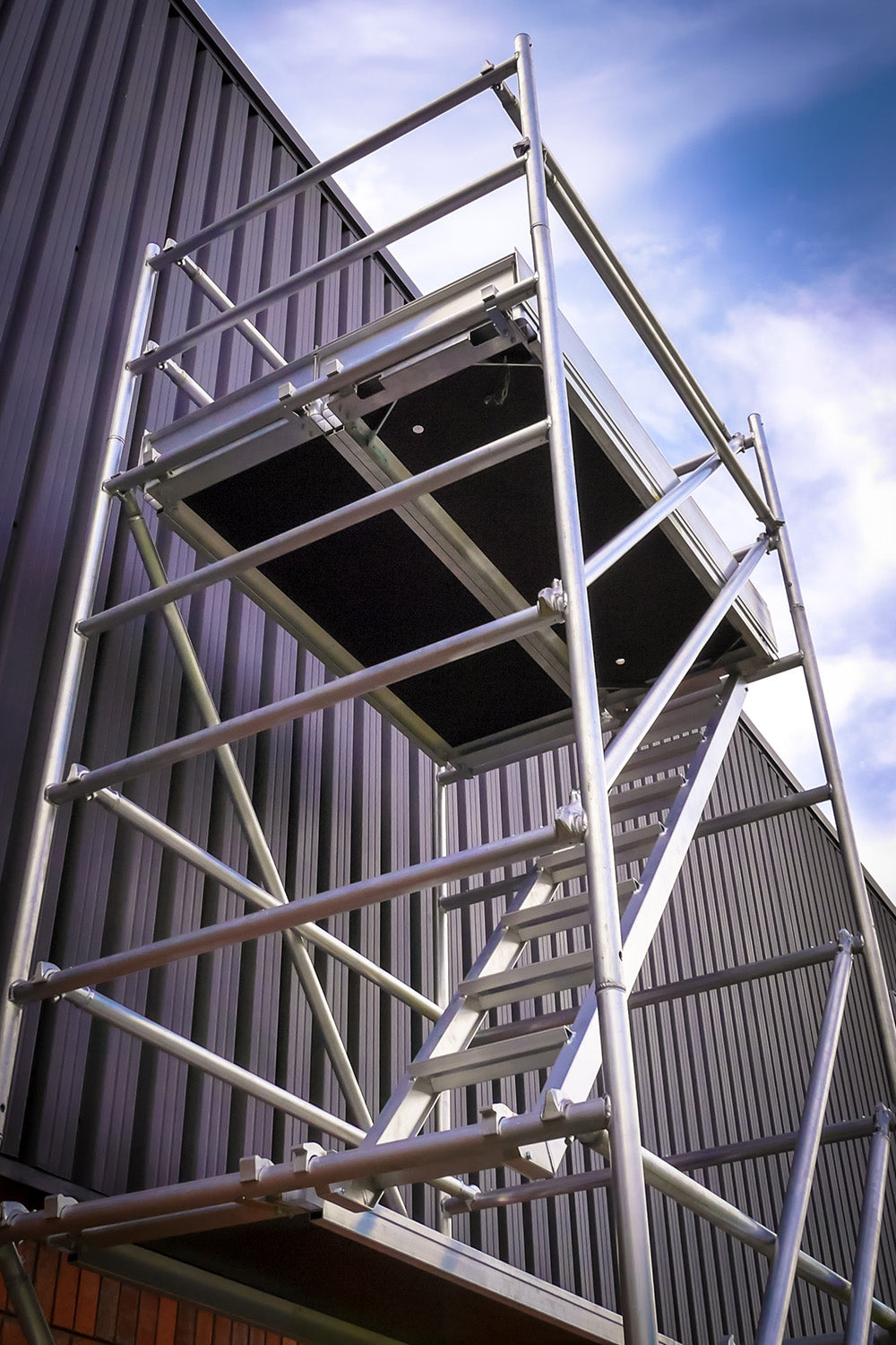 An Alto HD Stair Tower assembled next to an industrial building.