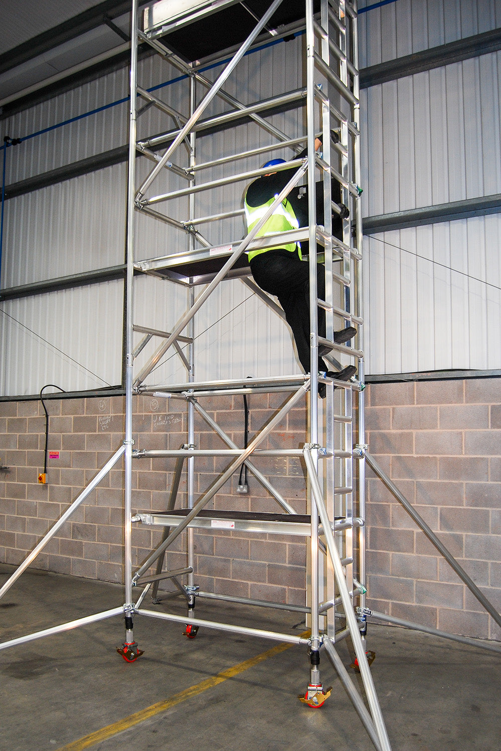 A man climbing an Alto Medium Duty single width tower with 1.6m long platforms.